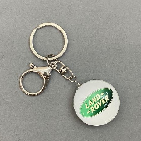 Breloc Auto Land Rover, diametrul aproximativ 35 mm, lungimea aproximativă 10 cm.
