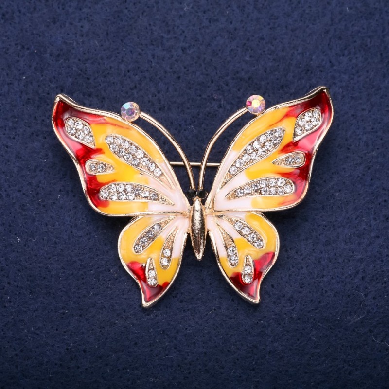 Broșă în formă de fluture, cu strasuri albe, email roșu și galben, 42×56 mm, metal auriu