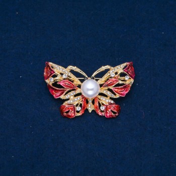 Broșă în formă de fluture, din metal auriu, email roșu, strasuri albe și o Mărgea de 46x30 mm +